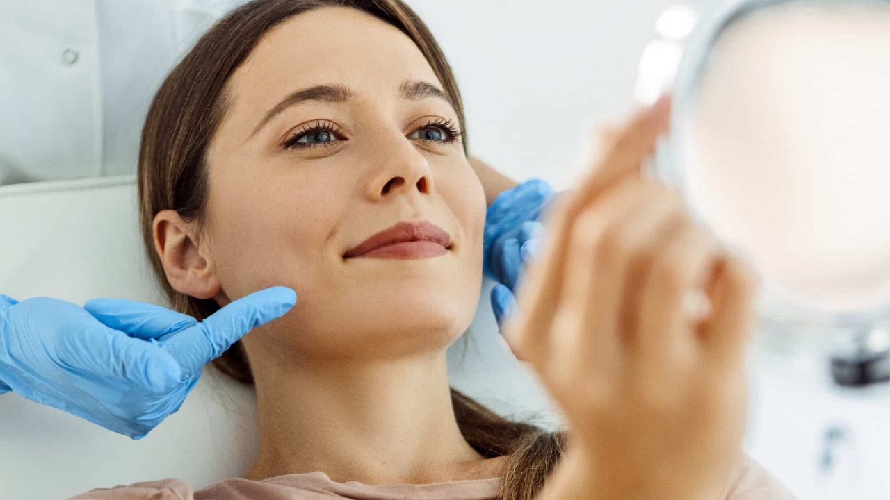 woman looks into mirror at medical Spa