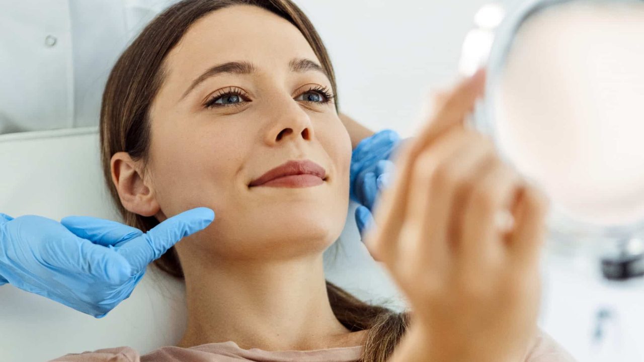 woman looks into mirror at medical Spa