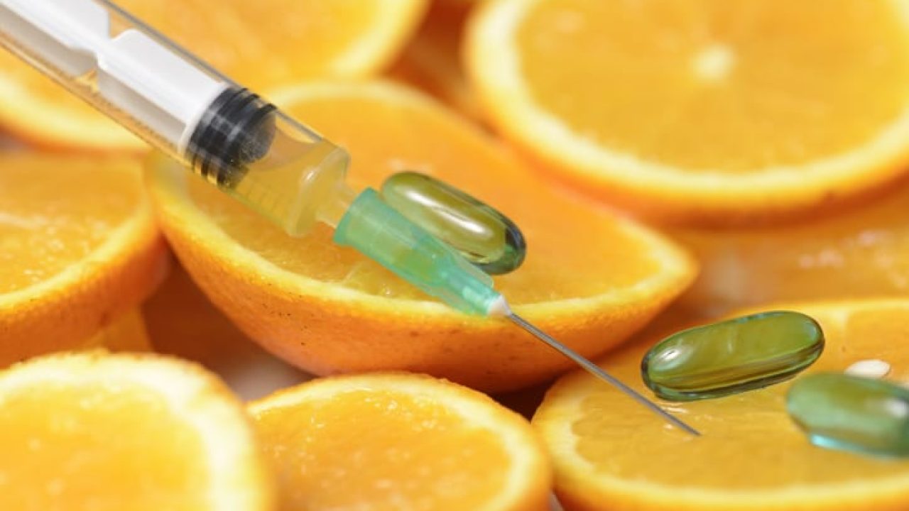 Slices of oranges with pills and a needle